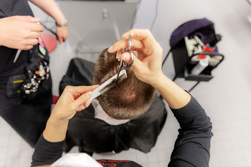 Kuvituskuva, kaksi opiskelijaa Stadin AO:ssa harjoittelee hiusten leikkaamista.