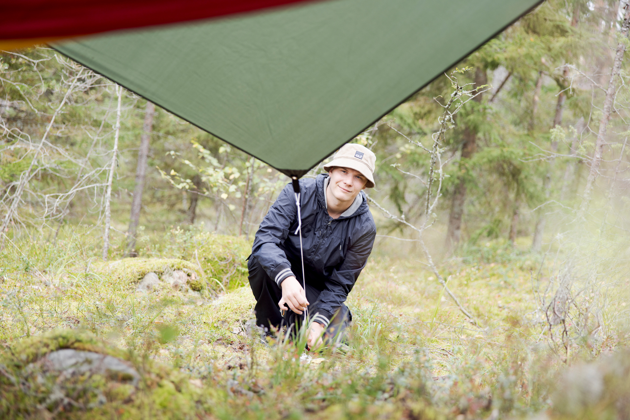 Luonto- ja ympäristöalan opiskelija pystyttää telttaa metsässä.